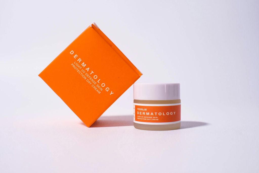 pexels photo 11472839 11472839 Bright orange dermatology cream packaging on white background for skincare advertisement.